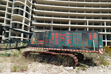 Rusty crane near unfinished construction