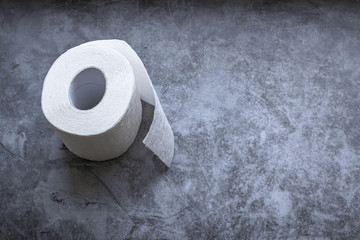 Roll of white soft toilet paper on dark background. Personal hygiene concept. Flat lay, top view. Copy space.