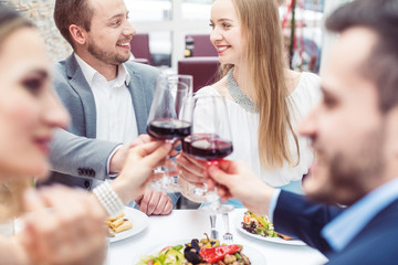 Cheerful people enjoying drink and food in Italian restaurant