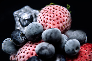 Macro view of frozen berries: strawberry, blueberry with ice cubes
