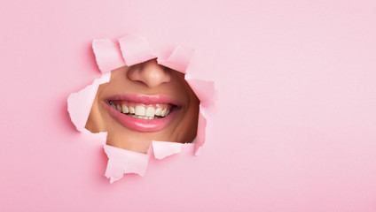 Woman showing lips out of pink paper hole
