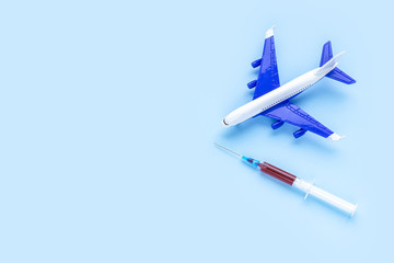 Airplane model and disposable syringe with blood samples isolated on blue background. Concept of coronavirus, COVID-19 pandemic, global quarantine. Flat lay, top view, copy space.