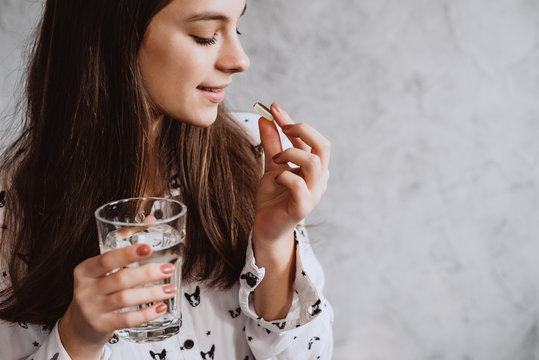 Diet. Nutrition. Smiling Girl Taking Pills With Oil Omega-3 Cod Liver And Holding A Glass Of Fresh Water In The Morning. The Concept Of A Healthy Eating And Lifestyle. Vitamin D, E, Fish Oil Capsules.