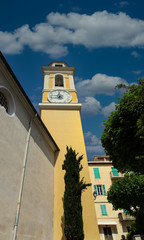Obraz premium Yellow clock tower in Villefranche, France under clear blue skies