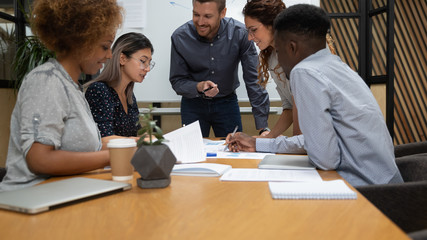 Diverse employees team working with documents, project statistics at meeting close up, sitting at table in boardroom, discussing results, financial report at briefing, sharing startup ideas