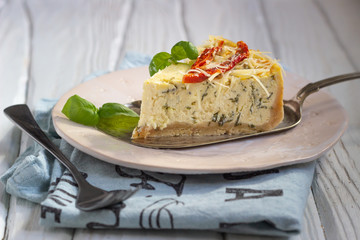 Savoury cheesecake with herbs decorated sun dried tomatoes, cheese and fresh basil.