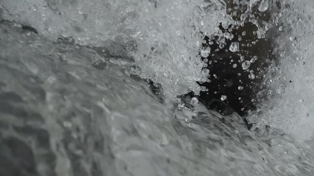 Small waterfall on river cascade in woodland in SLOW MOTION HD VIDEO. Sparkling stream of falling water in ravine. Water sprays drops and creates foam. Close-up. Half speed.