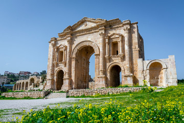 Fototapeta na wymiar Arch of Hadrian at the roman ruins of Jerash, Jordan. Front view on a sunny day with blue sky. It features some unconventional, possibly Nabataean, architectural features, such as acanthus bases.