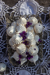 homemade meringues decorated with fresh violet flowers in a vintage metal candy cane