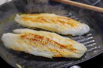 filet de tilapia en train de cuire dans une poêle