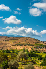 Naklejka premium Panoramic landscape of mountains and clouds and lovely field at foreground.