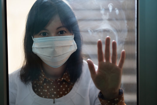 Coronavirus Spreading Prevention. Quarantine. Asian Woman In Protective Medical Mask Looking Through Locked Door Glass