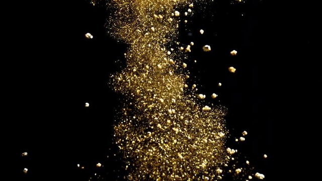 Stream of golden glitter underwater. Gold particles pouring in water on black background