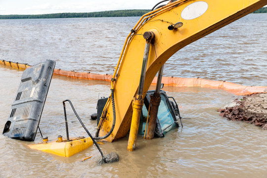 Close up of yellow excavator(construction equipment) drowned on the lake while working to strengthen the shore. Safety violation. Emergency at construction site