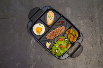 Breakfast, fried steak or cutlet, salad with tomato and green vegetables, croutons, potatoes, egg , view from the top, dark background. Concept healthy eating, diet, menu, nutritious food.