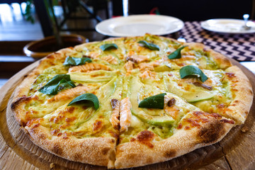 Pizza with salmon and avocado on a wooden tray
