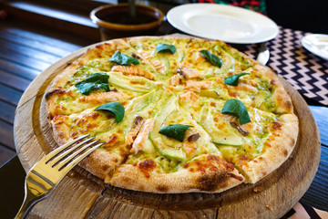Pizza with salmon and avocado on a wooden tray