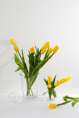 Fototapeta na wymiar bouquet of yellow tulips is on the table opposite white wall.
