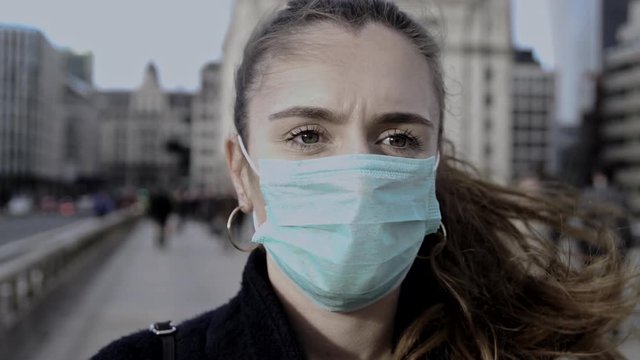 Panning around young woman wearing face mask while out in the streets of London