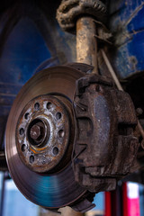 Car brake disc closeup on car service lifted for replacement