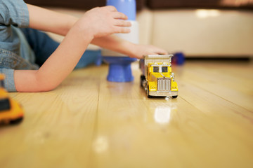 Little boy playing with toy car truck on wooden floor. 