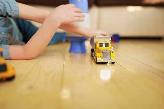 Little Boy Playing With Toy Car Truck On Wooden Floor. 