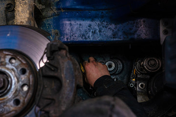 A car service worker carries out maintenance of the car after prolonged operation