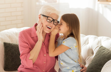 Little girl sharing secrets with her granny at home