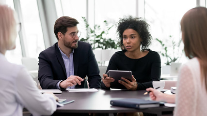 Multiracial colleagues coworkers brainstorm discuss company business project together, concentrated...