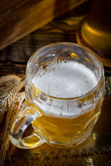Light frothing beer in a glass, on an old background.