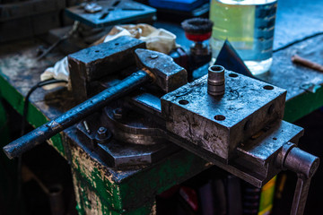 The hammer rests on a table clamped in a vise at a workplace in a car service