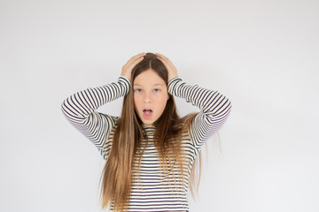 Girl in striped shirt with hands on her head surprised