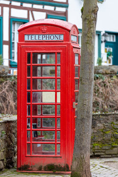 Red english telephone booth in front of a stone wall in Bad Muenstereifel