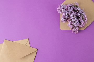 Spring flowers. blooming lilac flowers in a craft envelope on a bright purple background. top view