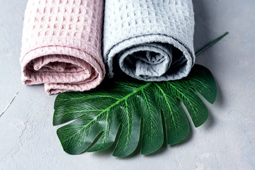 Two Towels Tolled Up on a Gray Background Pink and Gray Towels Horizontal Copy Space Monstera Leaf