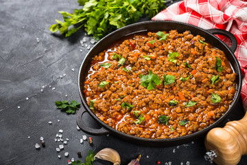 Bolognese sause in iron plate at black table.