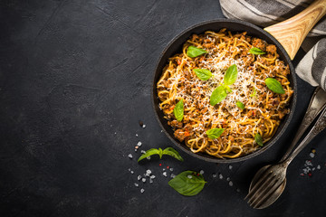 Pasta Bolognese in the skillet at black table.