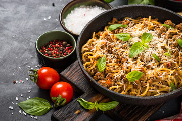 Pasta Bolognese in the skillet at black table.
