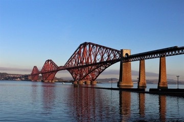 Fototapeta na wymiar puente rojo de construcción moderna, sobre un río, en el que está pasando un tren