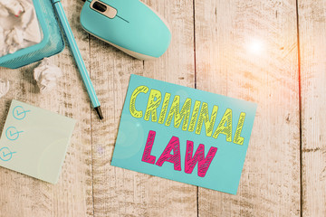 Writing note showing Criminal Law. Business concept for legal system which relates to punishing those commits crime Crumpled paper in bin and computer mouse on wooden backdrop.