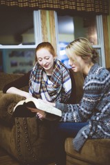 Young female friends sitting on the couch and discussing the Bible