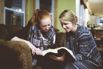 Young female friends sitting on the couch and discussing the Bible