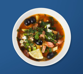 Russian Solyanka soup in a white deep plate. View from above. On a light background