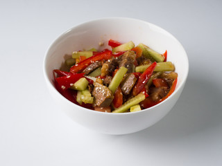 Korean meat salad in a white bowl. Juicy salad of beef, cucumbers, peppers. Side view