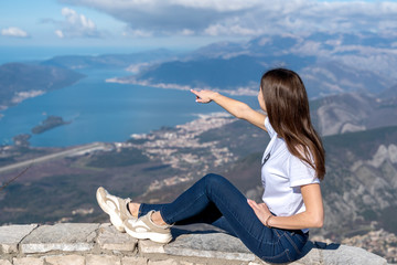 Traveler girl points finger hand to landscape. Vacation trip concept. Montenegro