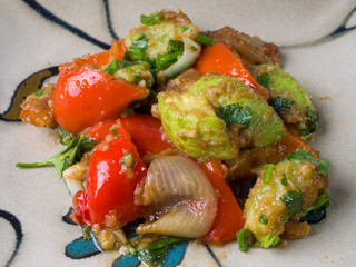 Hot salad of zucchini and pepper on a square plate. Close-up