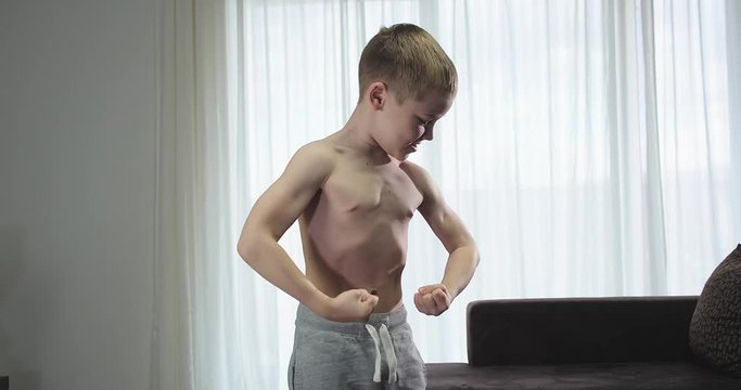 Happy child doing sports at home, boy fitness training dumbbells