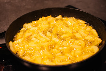 Sliced potatoes frying in pan. Unhealthy food. Typical american food