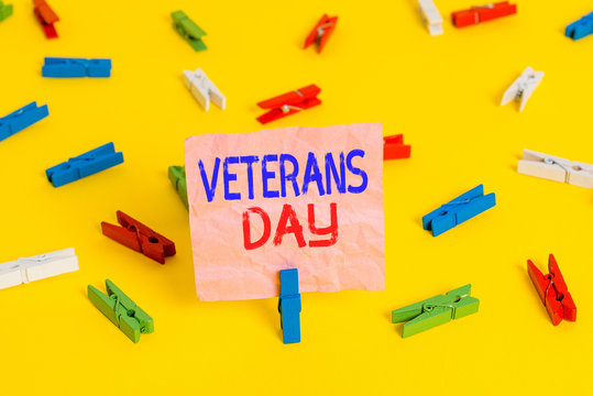 Handwriting text Veterans Day. Conceptual photo a public holiday to honour US veterans and victims of all wars Colored clothespin papers empty reminder yellow floor background office