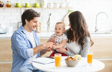 Obraz na płótnie Canvas Millennial parents working at kitchen with baby